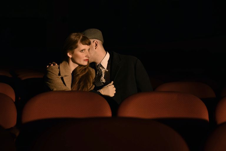 A classic cinematic scene of a couple sharing a romantic moment in a theater.